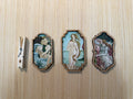 Three framed artworks on a wooden surface with a clothespin on the left.